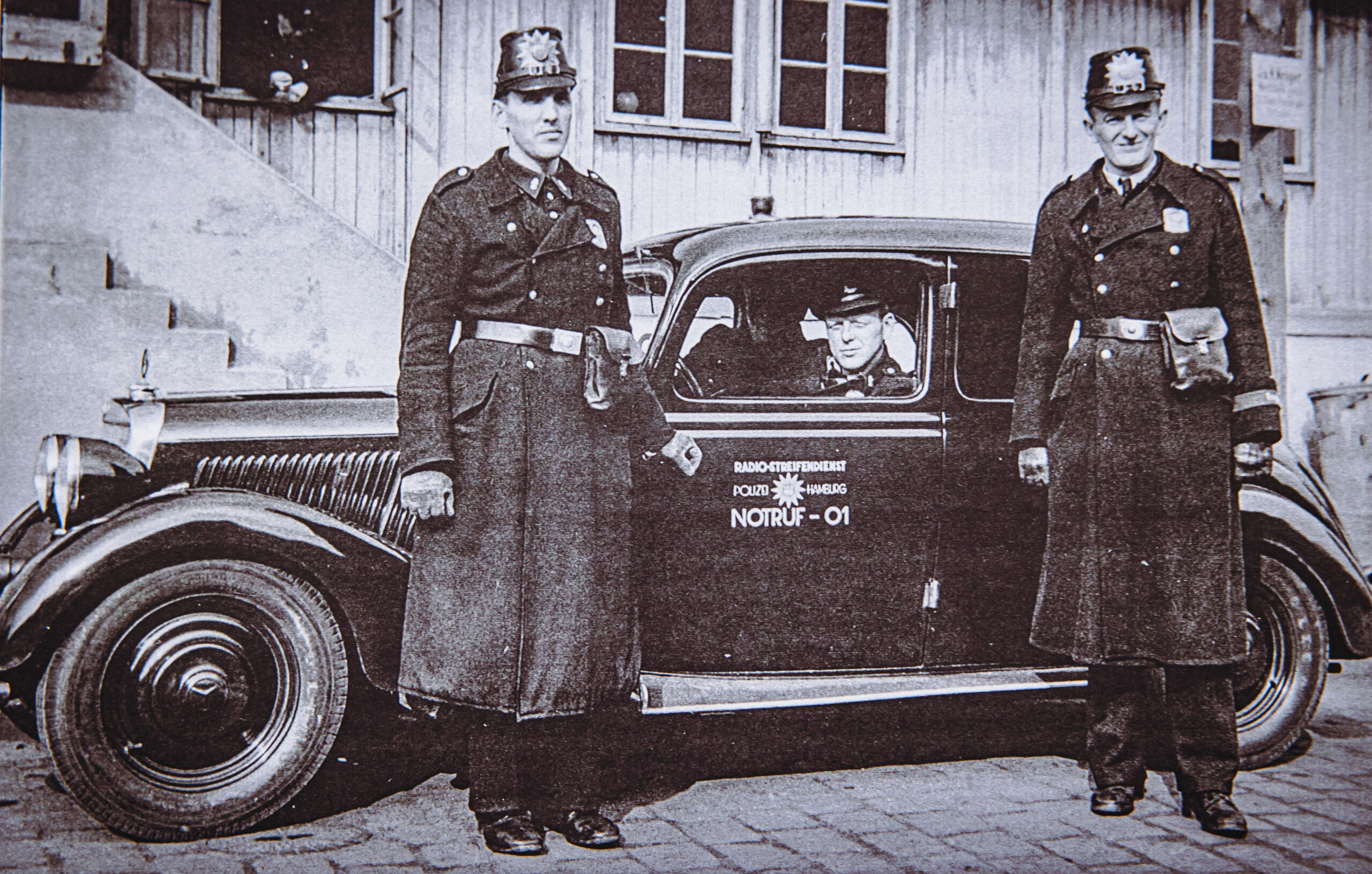 Polizisten vor sehr altem Auto
