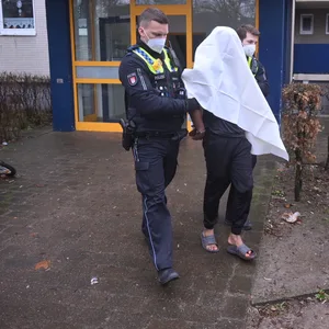 Polizisten führen einen Verdächtigen am Wagrierweg ab.