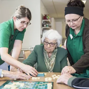 Pflegekräfte spielen mit alten Menschen.