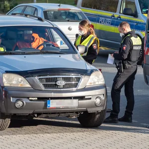 Polizisten kontrollieren die Insassen eines Kia.
