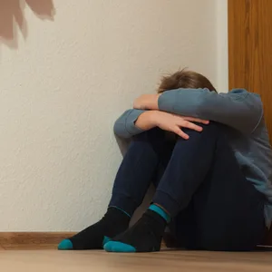 Ängstlicher Mann versteckt im sitzen seinen Kopf zwischen seinen Beinen
