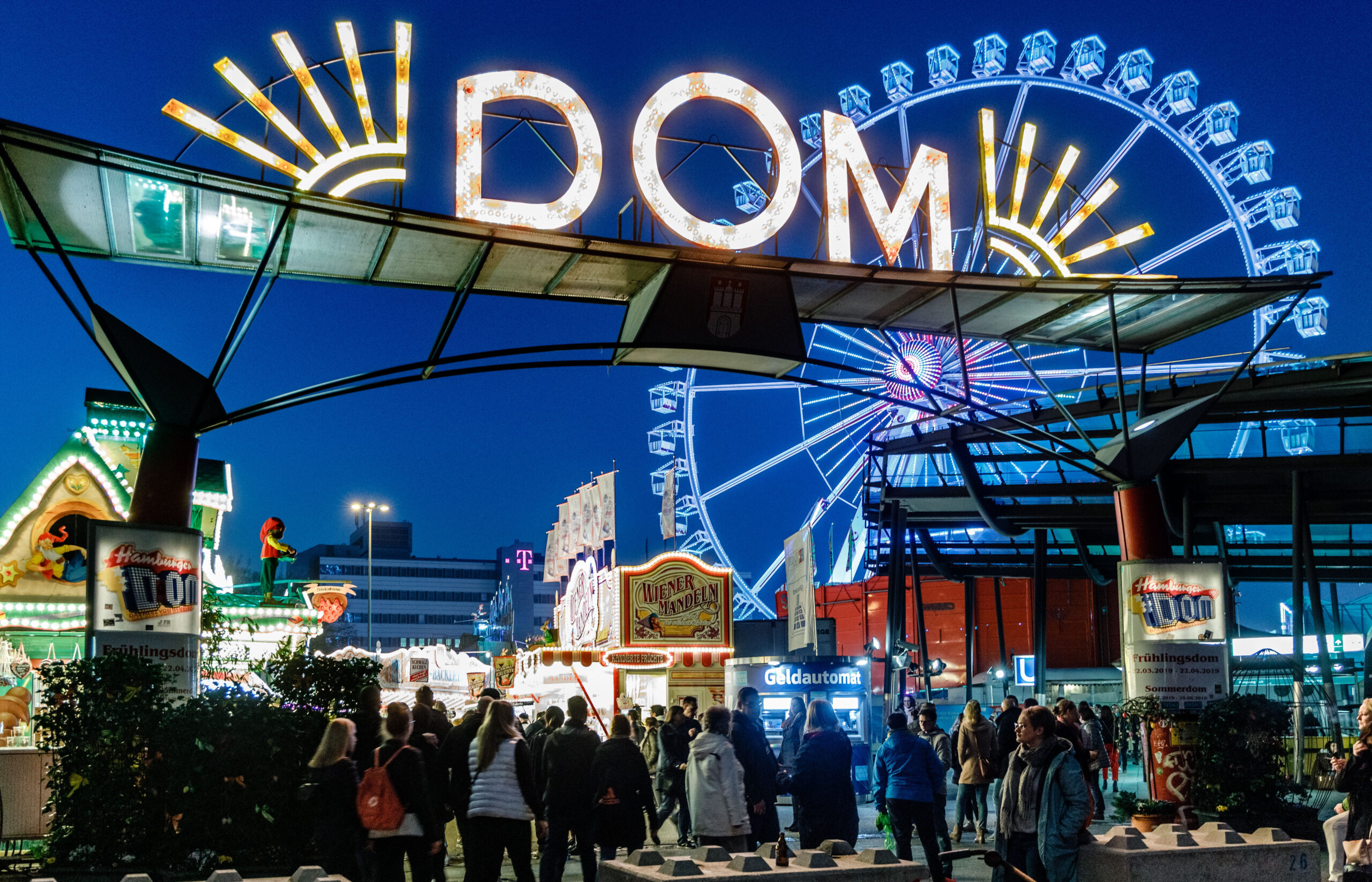 Eingang zum Hamburger Frühlingsdom mit Leuchtreklame und Riesenrad