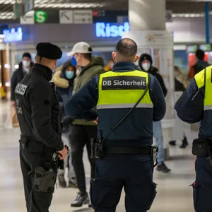 Sicherheitskräfte der Deutschen Bahn mit Polizist am Bahnhof.