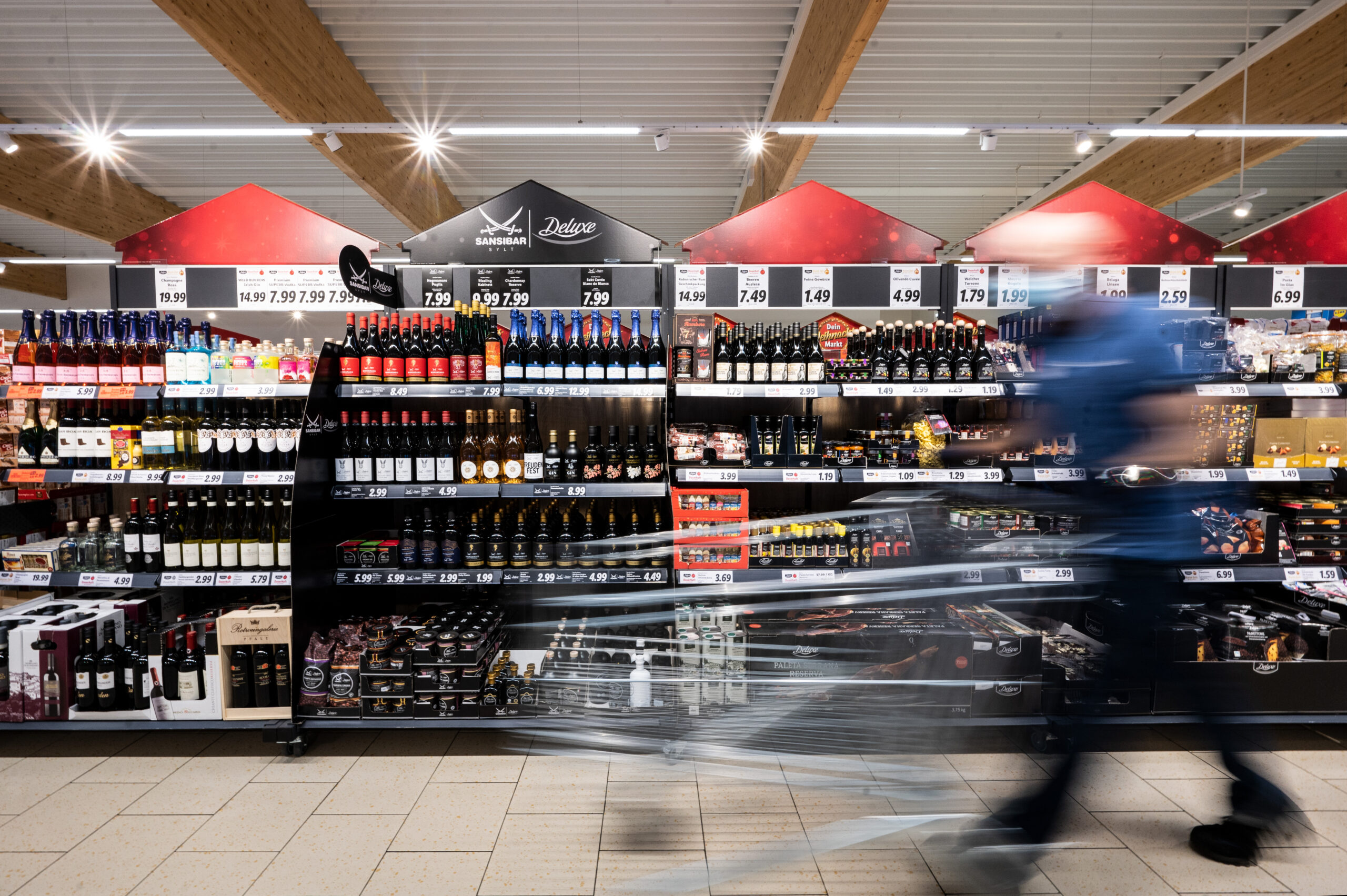 Symbolbild: Ein Mann geht mit seinem Einkaufswagen in einer Lidl-Filiale an Regalen vorbei