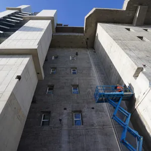 Ein Bauarbeiter bereitet die Montage der Halterungen des Aufgangs zum Garten auf dem Dach des Hochbunkers an der Feldstraße an der Außenfassade vor.