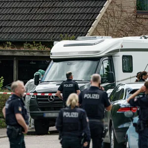 Tatort Dänischenhagen bei Kiel. Polizisten vor Absperrband vor einem Haus.