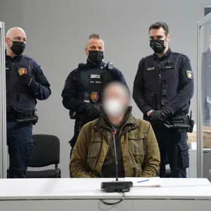 Der Angeklagte Hartmut F. im Landgericht Kiel, bewacht von drei Justizbeamten.