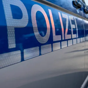 Polizeiwagen vor einer Gruppe Menschen.