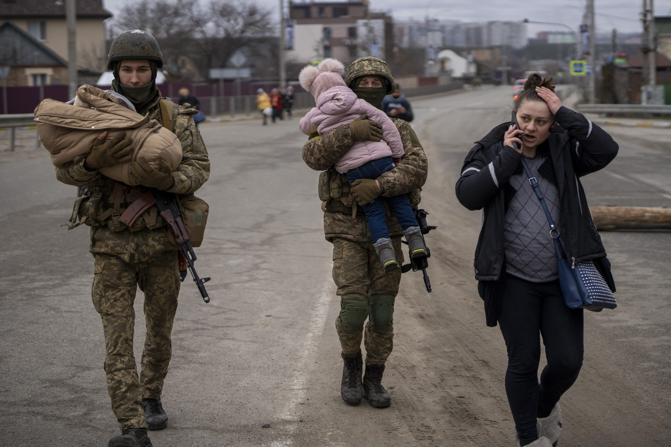 Ukrainische Soldaten tragen Babys und helfen einer fliehenden Familie in Irpin.