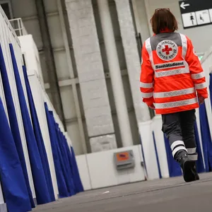 Eine freiwillige Helferin des Roten Kreuz geht durch die Reihen mit Notunterkünften für Geflüchtete in den Hamburger Messehallen.