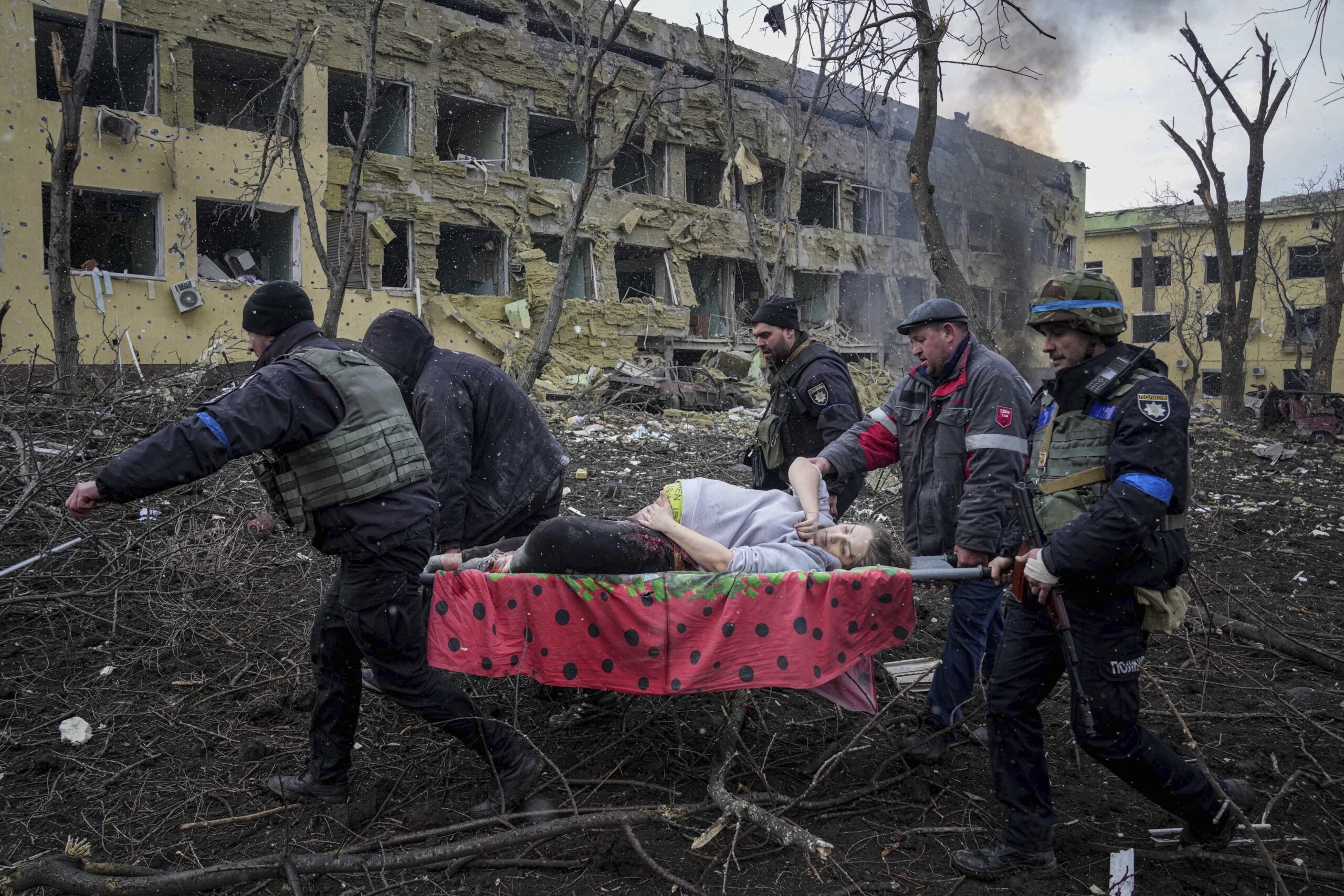 Ukrainische Rettungskräfte und Freiwillige tragen eine verletzte schwangere Frau aus einer Entbindungsklinik in Mariupol.