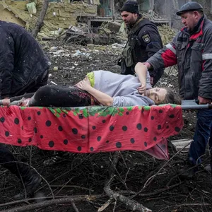 Ukrainische Rettungskräfte und Freiwillige tragen eine verletzte schwangere Frau aus einer Entbindungsklinik in Mariupol.