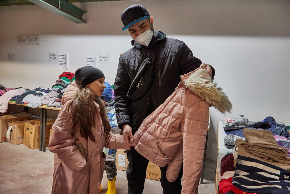 Ukrainische Geflüchtete mit einer Kinderjacke in der neuen Rissener Kleiderkammer.