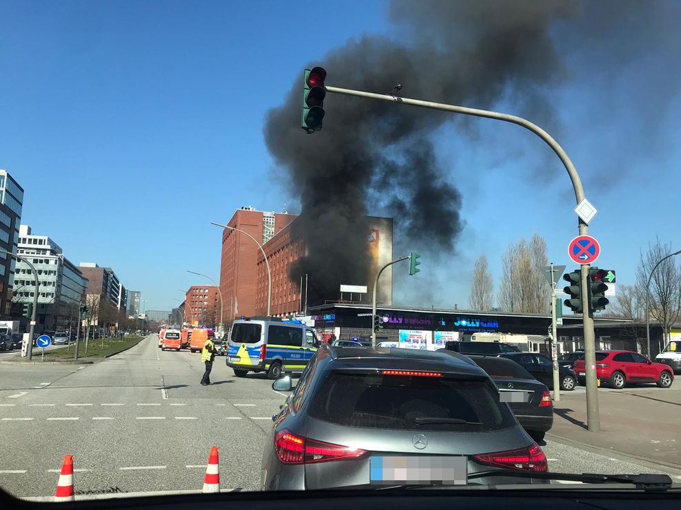 Autos stehen im Stau, neben einem Gebäude steigt schwarzer Rauch auf