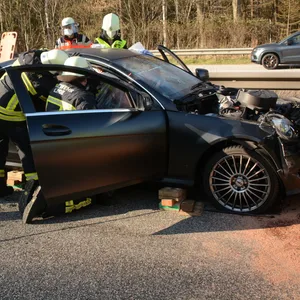 Mehrere Feuerwehrleute stehen um eine schwarze Limousine und schneiden das Dach ab
