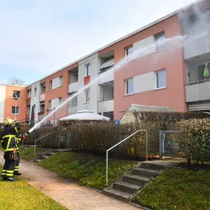Zwei Feuerwehrmänner bei den Löscharbeiten an einem Balkon in Hamburg-Hausbruch
