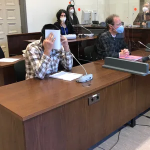 Der Angeklagte T. verbirgt vor Gericht sein Gesicht.