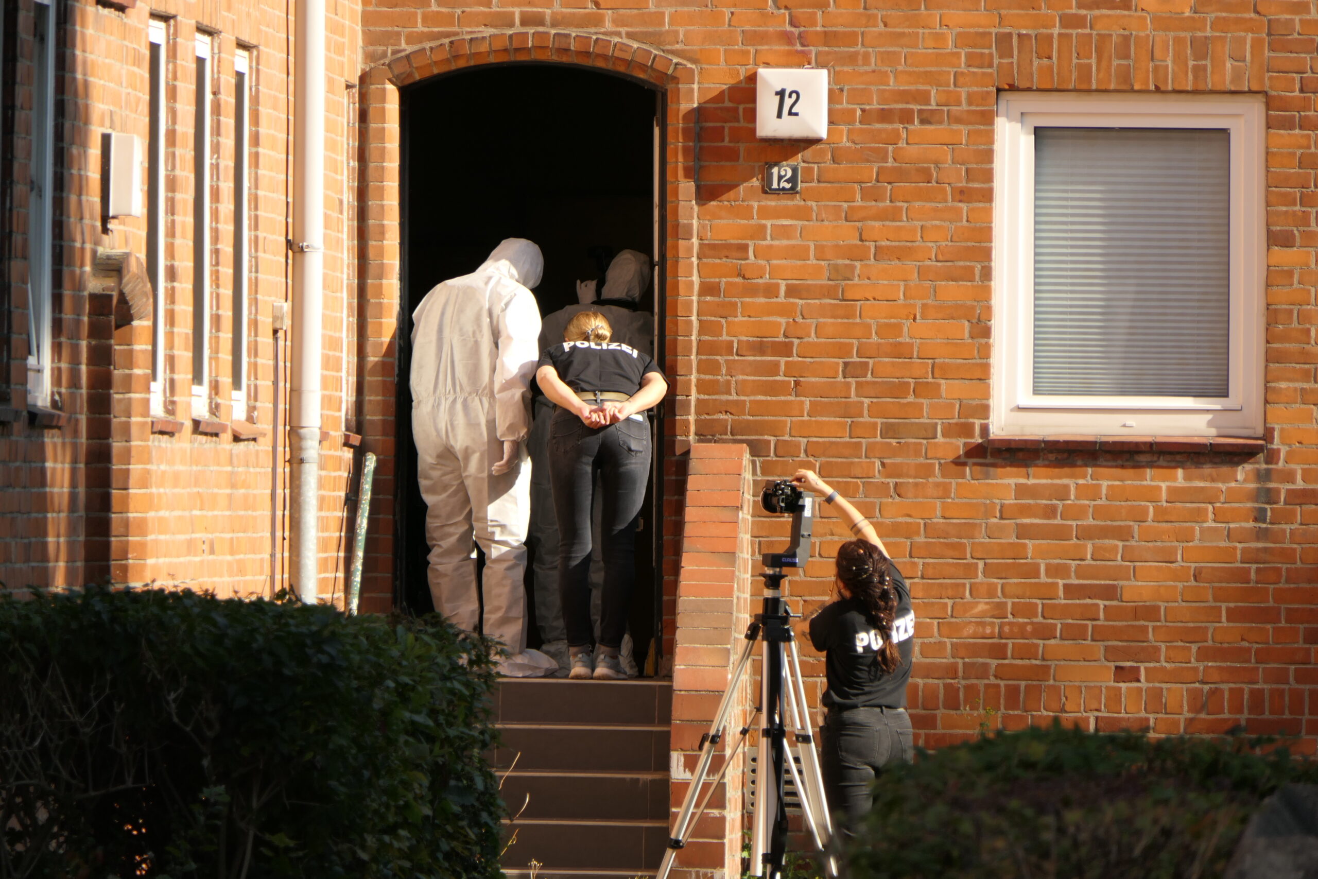 Ermittler vor dem Mehrfamilienhaus in Kiel, in dem ein 22-Jähriger schwer verletzt wurde.