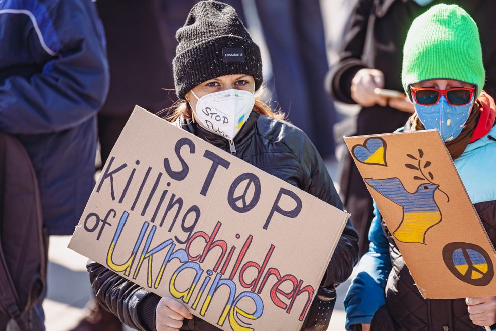 Auf dem Plakat der Demonstrantin steht: „Stop killing children of Ukraine“.