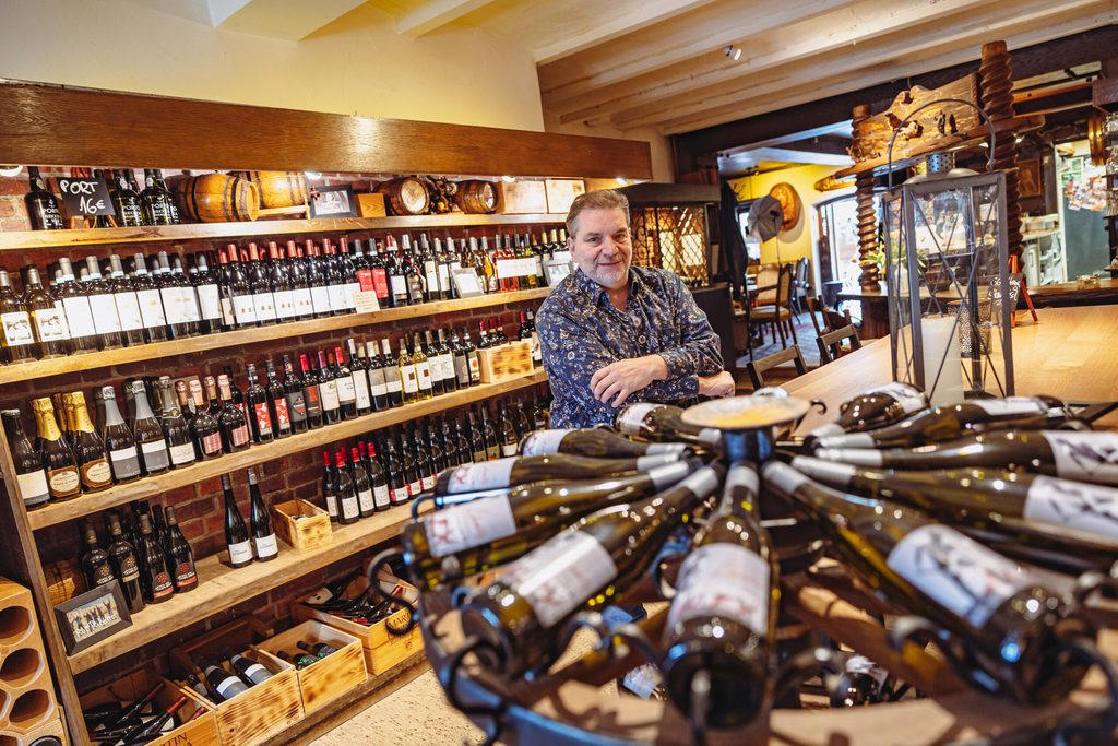 Bernd Lehmitz steht vor einem vollen Weinregal.