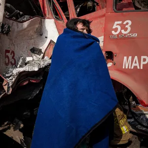 Eine Frau bedeckt sich in Mariupol mit einer Decke nach einem Beschuss.