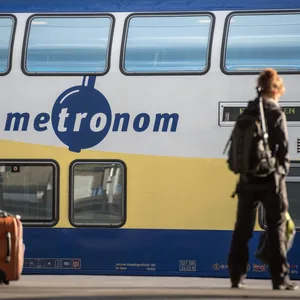 Ein Metronom-Zug steht im Bahnhof, davor ein Fahrgast sowie Gepäck.