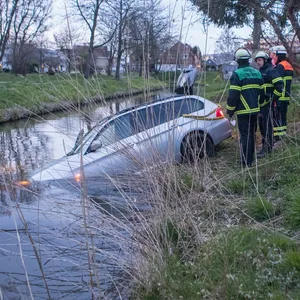 Feuerwehrleute vor dem in den Graben gefahrenen BMW in Hamburg-Finkenwerder.