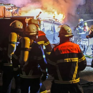 Feuerwehrleute vor dem brennenden Boot.