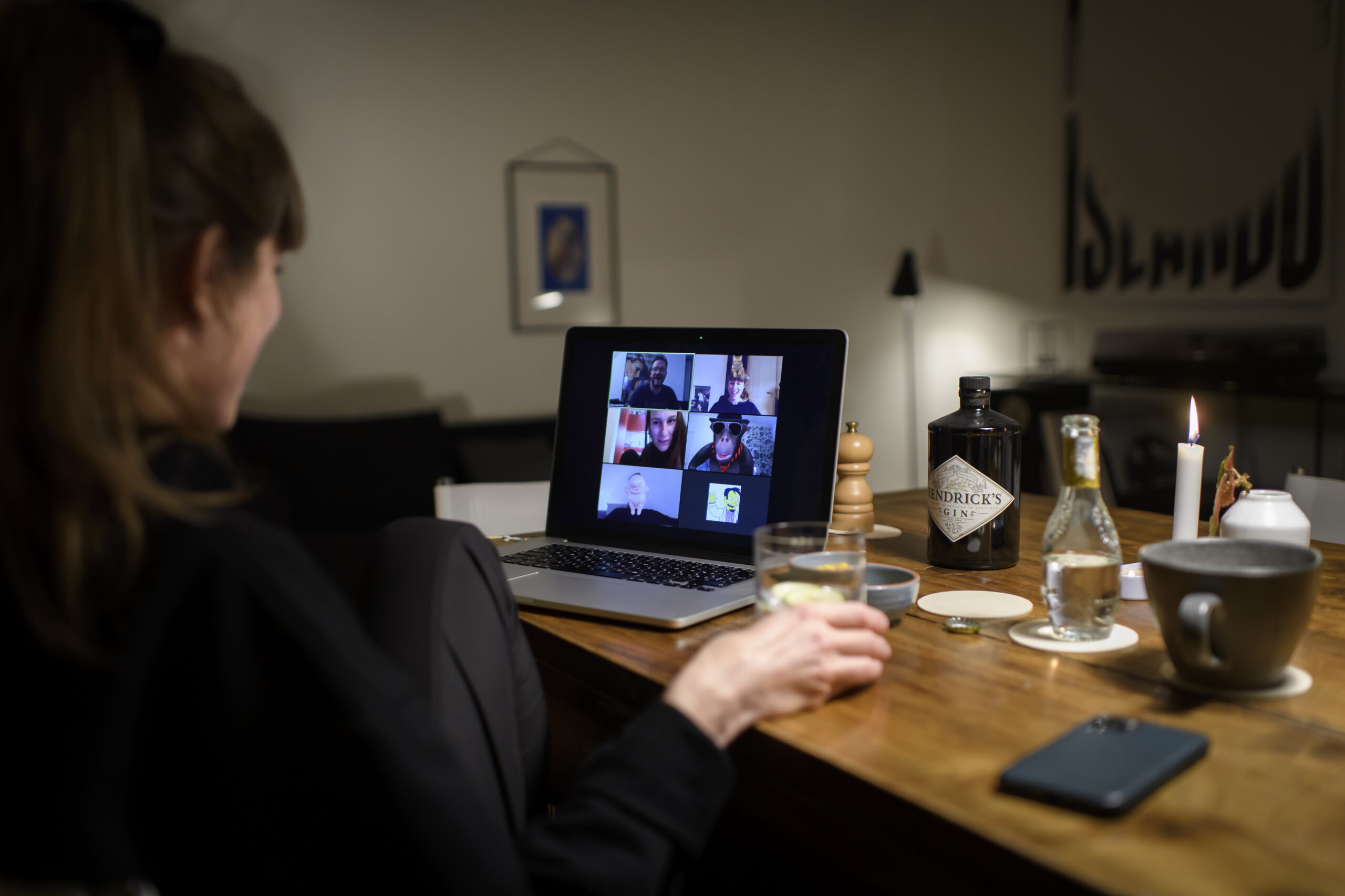 Frau in ihrem Wohnzimmer sitzt vor ihrem Laptop und ist in einer Videokonferenz.