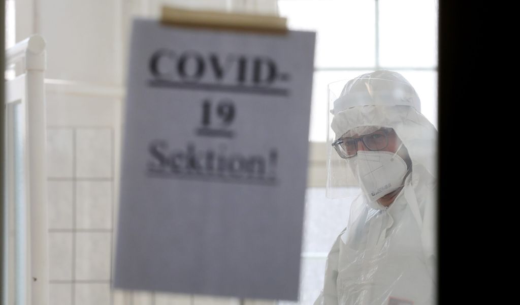 Rechtsmediziner im Leichenhaus blickt auf ein Schild mit der Aufschrift „COVID-19 Sektion!“