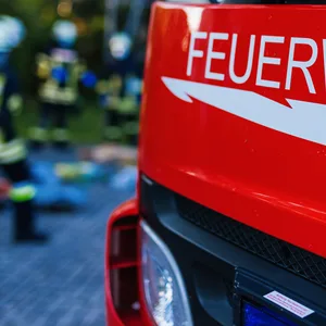 Ein Feuerwehrauto mir Einsatzkräften im Hintergrund.