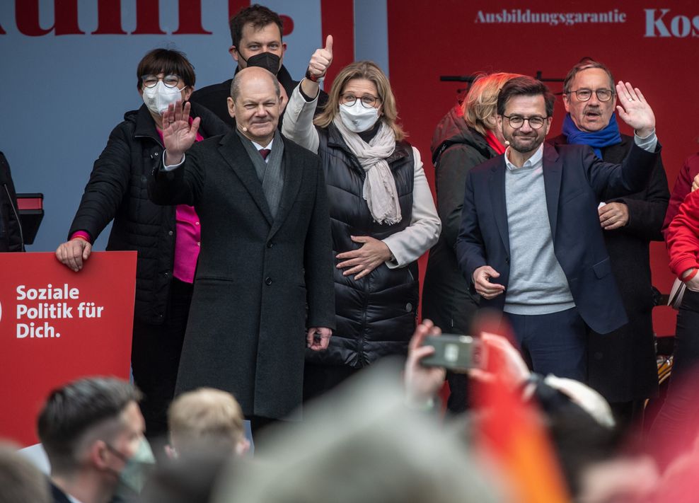 Mehrere Personen stehen auf einer Bühne und winken dem Publikum zu