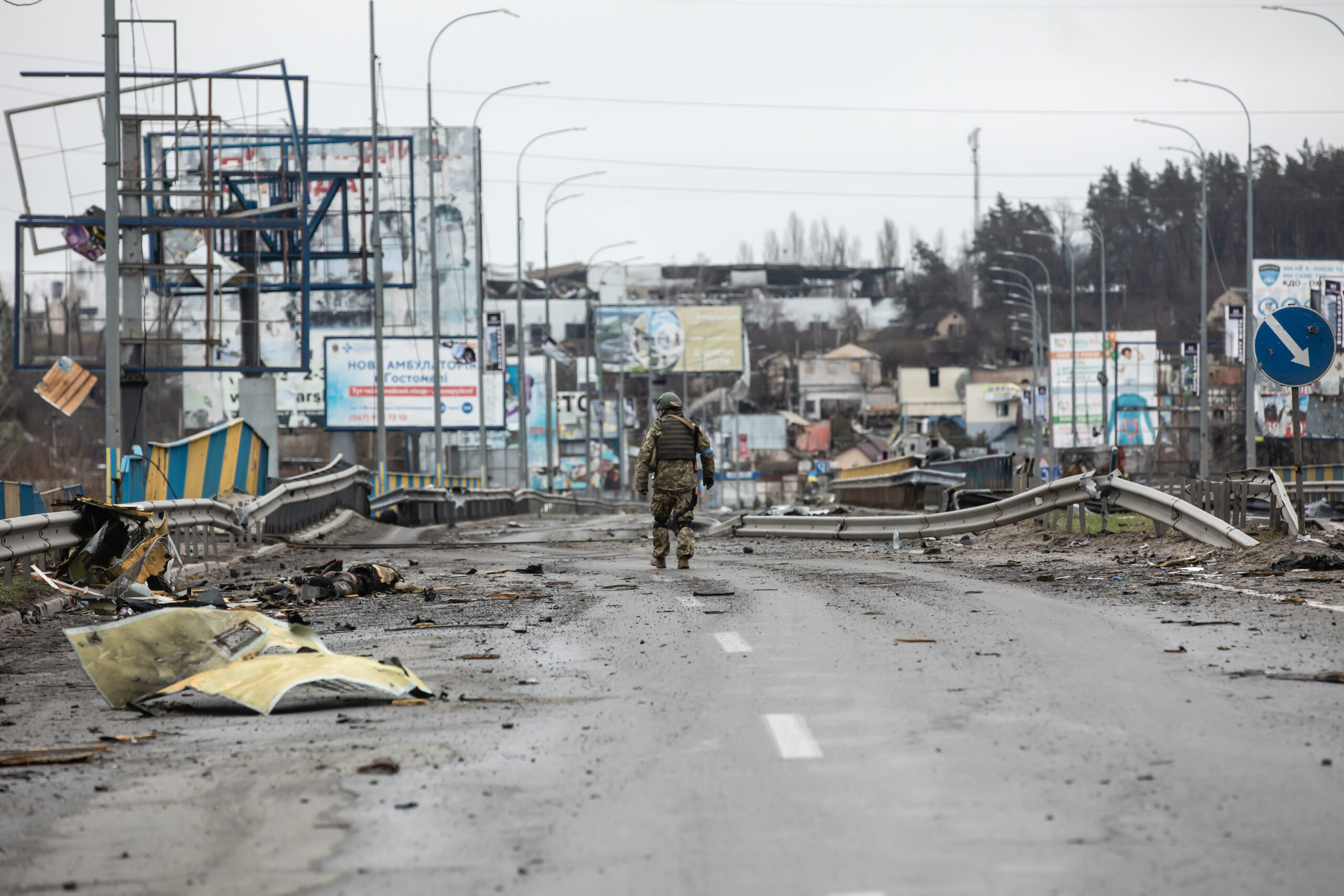 Ein ukrainischer Soldat geht entlang von Leichen auf einer zerstörten Straße in Bucha.