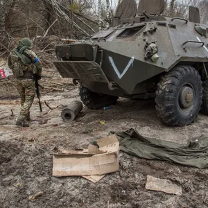 Ein ukrainischer Soldat geht an einem Schützenpanzer russischer Streitkräfte vorbei auf einer Straße in der Nähe von Tschernobyl.