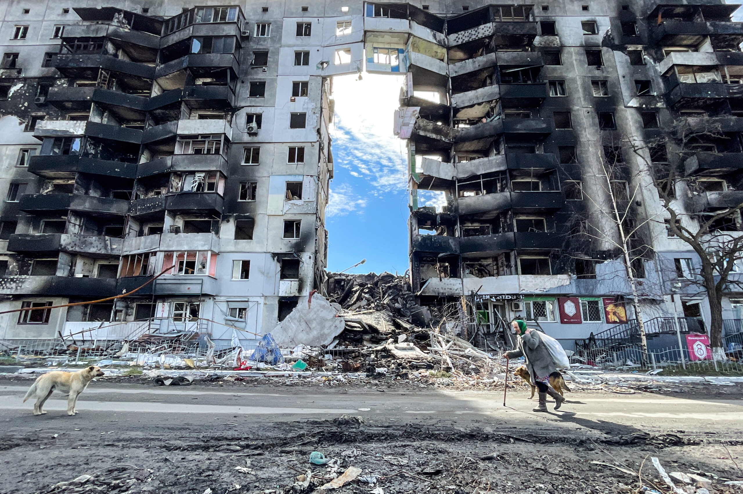 Eine ältere Frau geht in Borodjanka an einem durch einen russischen Luftangriff beschädigten Wohnhaus vorbei.
