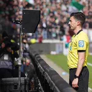Schiedsrichter Florian Badstübner steht am Monitor am Spielfeldrand im Millerntor