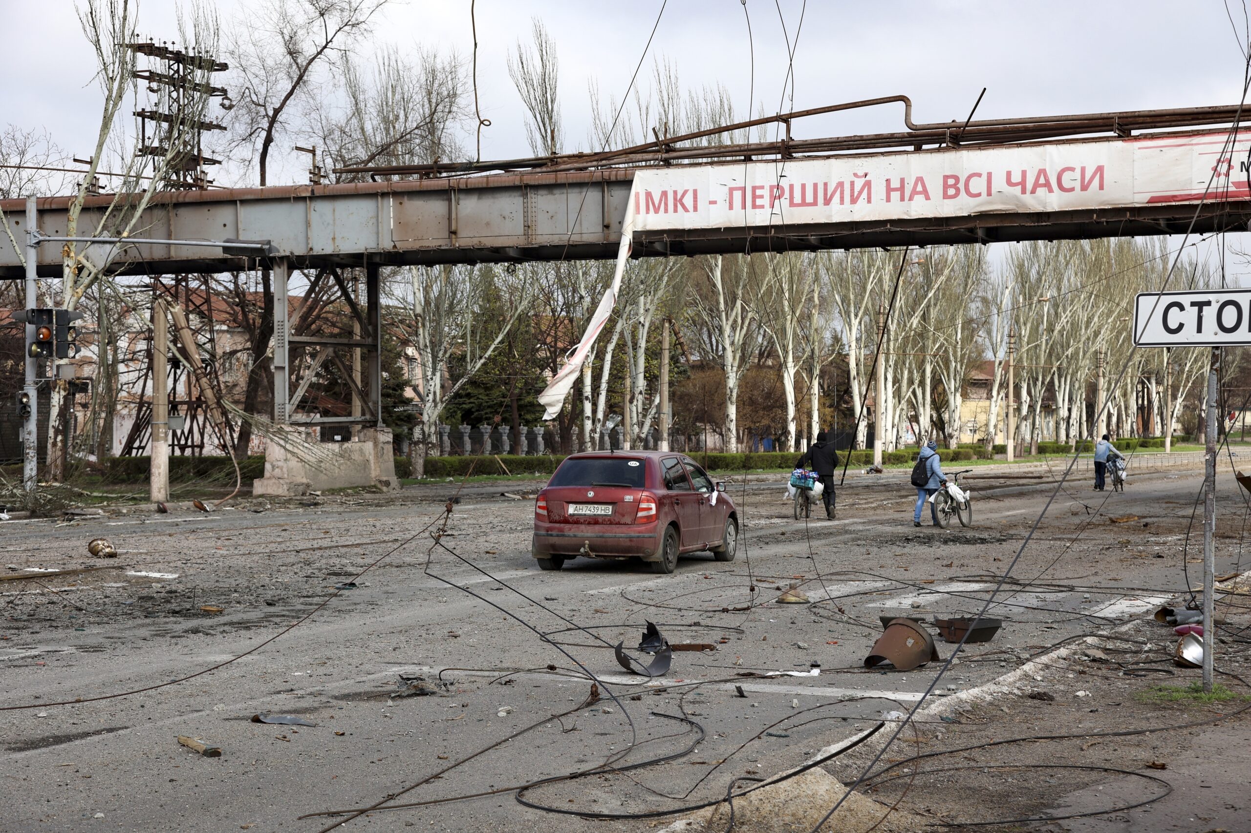 Anwohner gehen an einem zerstörten Teil des zweitgrößten Metallurgieunternehmens der Ukraine vorbei