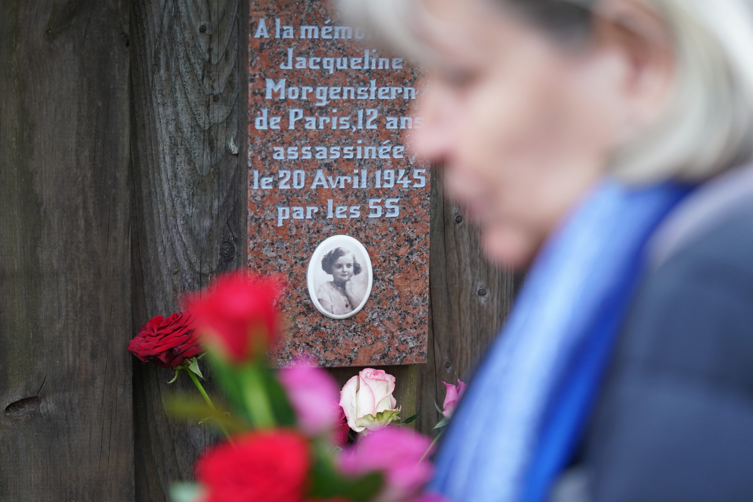 Eine Frau steckt Rosen an den Gedenktafeln der getöteten Kinder im Rosengarten der Gedenkstätte Bullenhuser Damm.