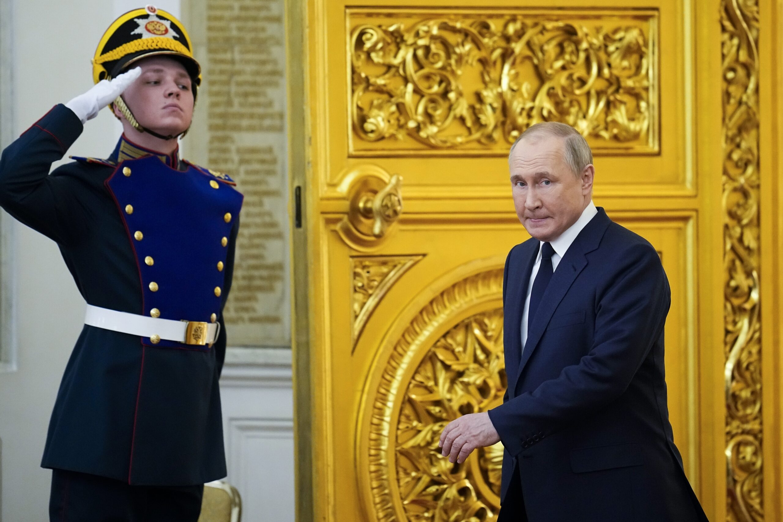 Putin läuft durch eine goldene Tür, neben ihm salutiert ein Wachmann