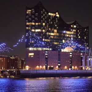 Beleuchtete Drohnen fliegen über der Elbe vor der Elbphilharmonie im Rahmen der Eröffnung des Musikfests Hamburg.