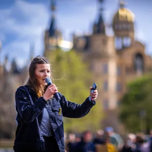 Luisa Neubauer steht auf einer Bühne vor dem Schweriner Schloss.