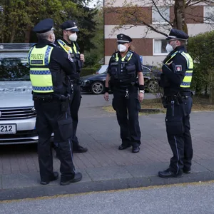 Polizisten stehen neben einem Streifenwagen