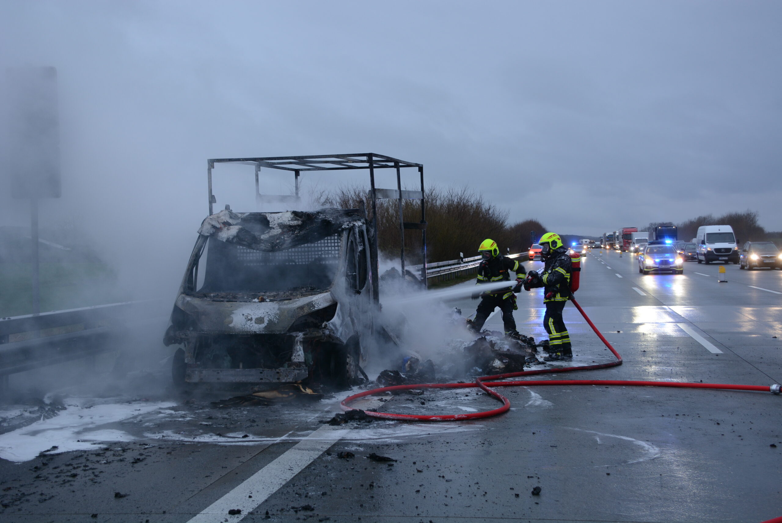 Feuerwehrkräfte löschen den in Flammen aufgegangen Transporter auf der A1.