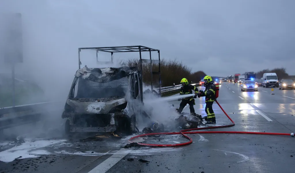 Feuerwehrkräfte löschen den in Flammen aufgegangen Transporter auf der A1.
