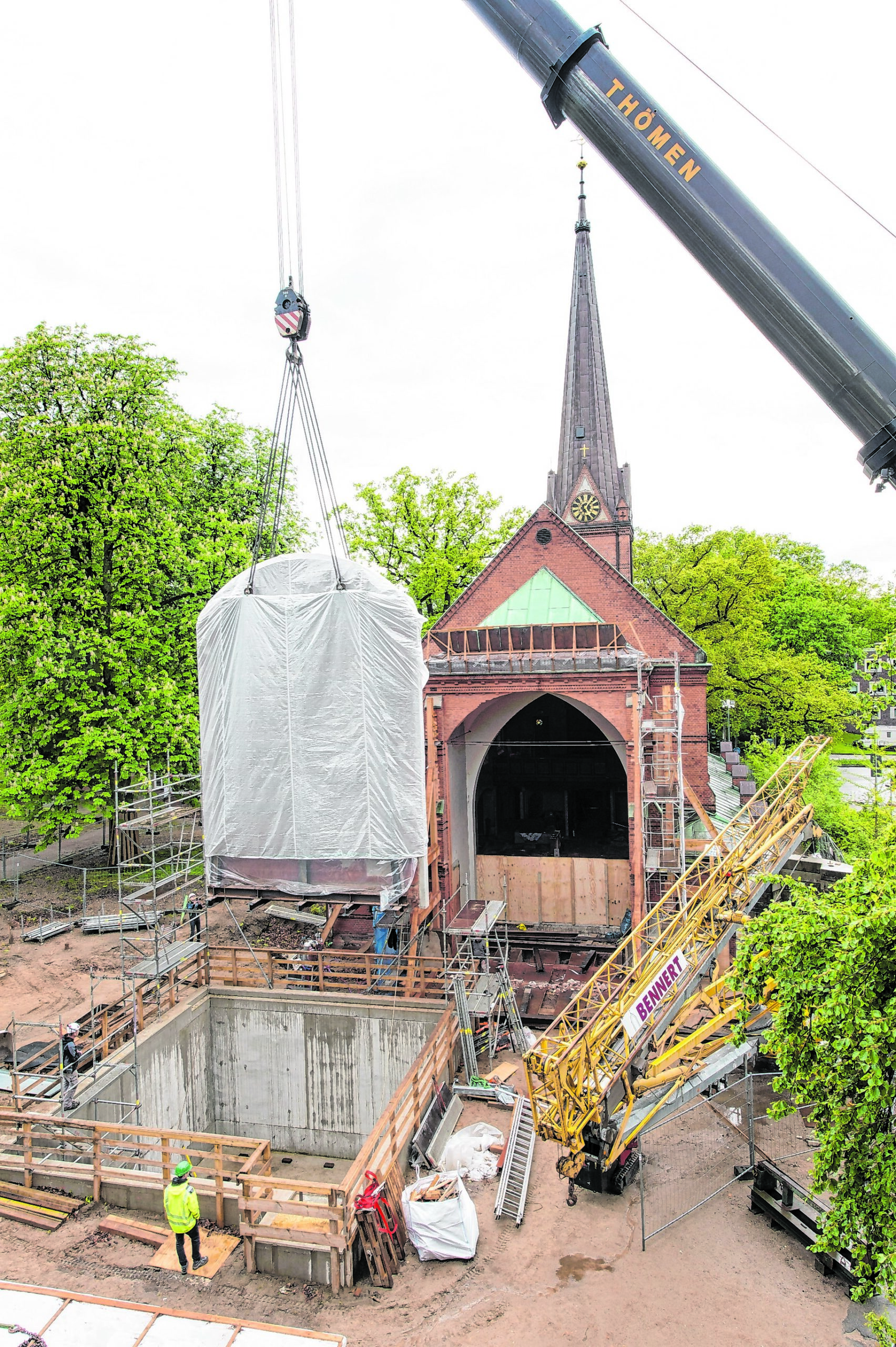 Ein Telekran hebt die 58 Tonnen schwere und 12 Meter hohe Kirchenwand an den neuen Standort hinter der Kirche.