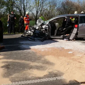 Die Front eines silbernen Autos ist völlig zerstört, drumherum stehen mehrere Einsatzkräfte von Polizei und Feuerwehr