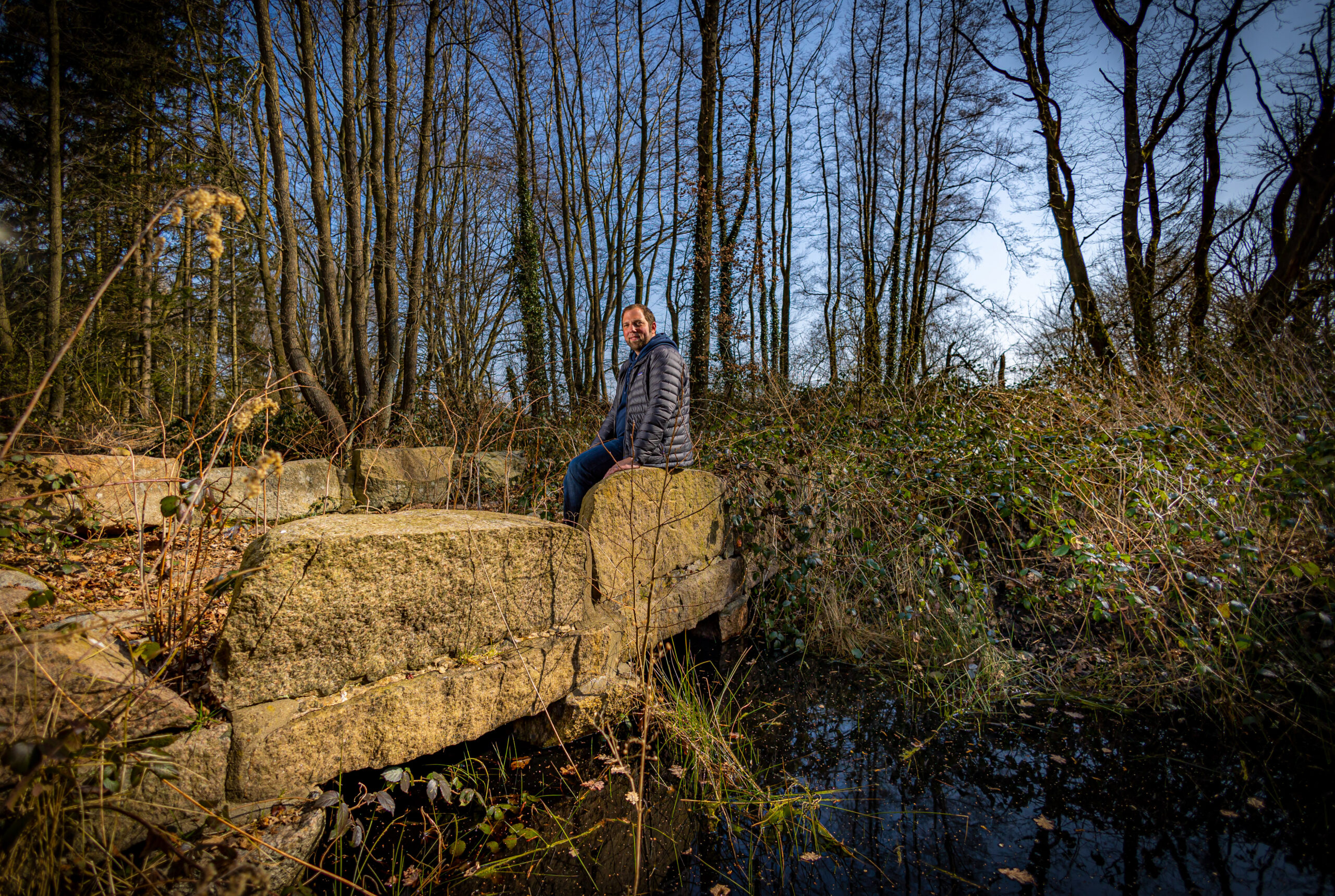 Mann sitzt auf alter Steinbrücke