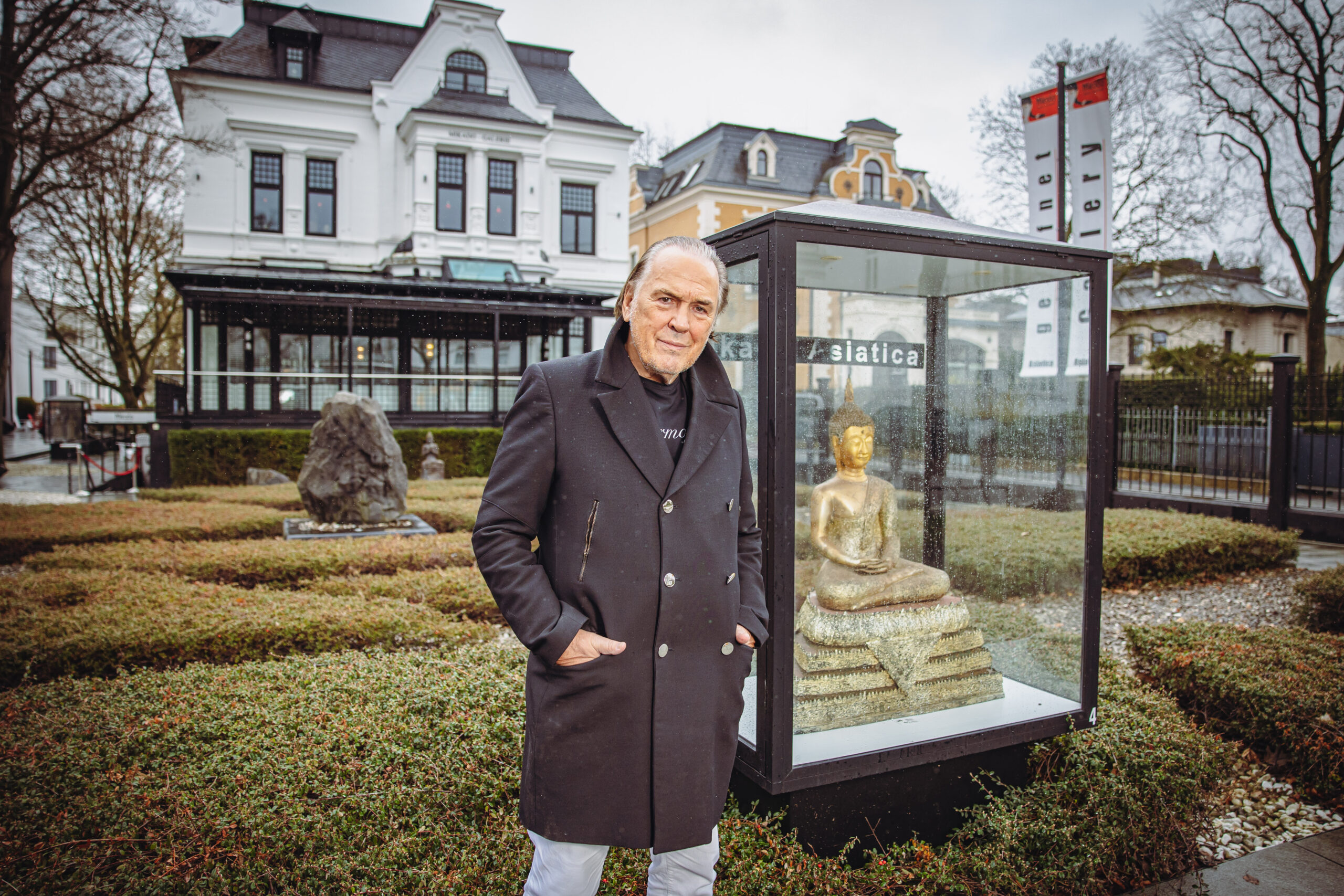 Mann steht neben Vitrine mit Buddha