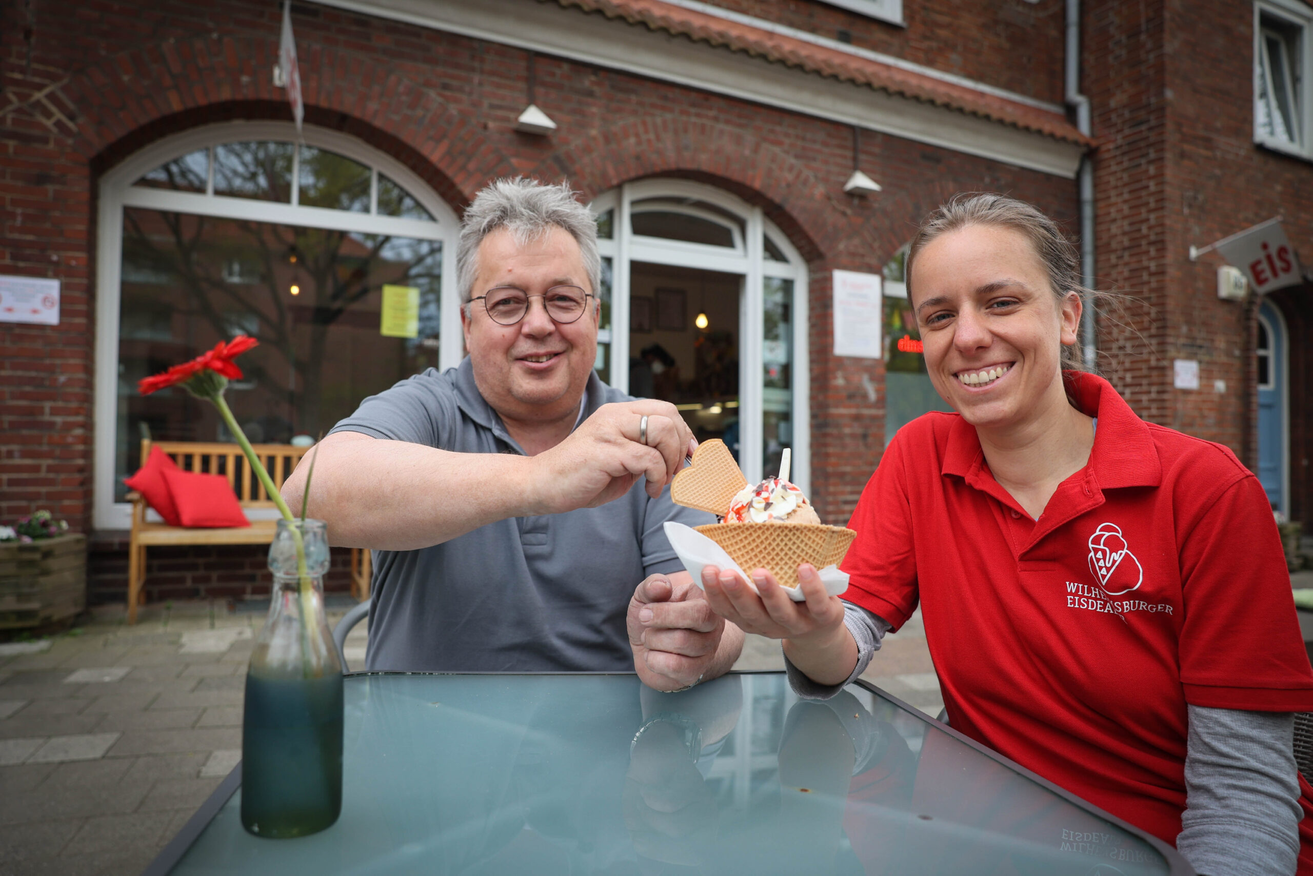 Dieter Kalvelage und Clarissa Wirth halten vor ihrem Eiscafé einen Eisbecher in den Händen.
