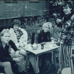 Schwarzweiß-Foto aus dem Video. Die Toten Hosen sitzen draußen im Grünen an einem Tisch und trinken Tee